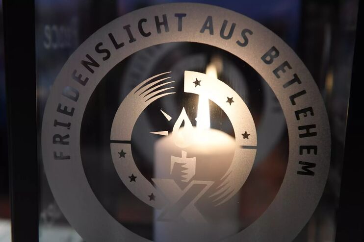 Eine Kerze hinter einem Logo mit der Aufschrift Friedenslicht aus Bethlehem