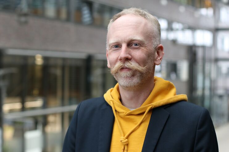 Eine männlich zu lesende Person schaut in die Kamera