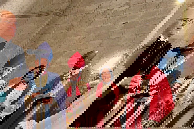 Mehrere als Männer lesbare Personen in Bischofskleidung stehen zusammen.