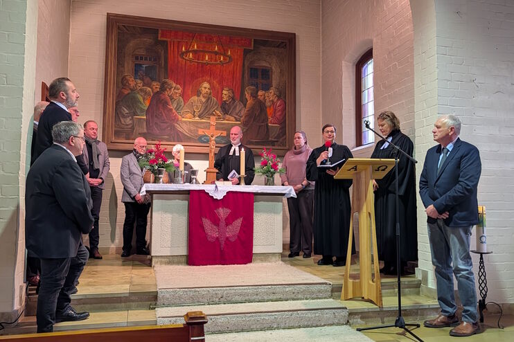 Eine Gruppe aus als Männer und Frauen lesbaren Personen steht im Altarraum einer Kirche.