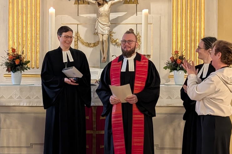 Drei Personen stehen neben einer männlich gelesenen und applaudieren.