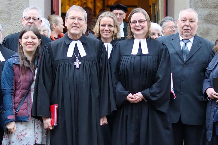 Menschen in Talar und Festkleidung.