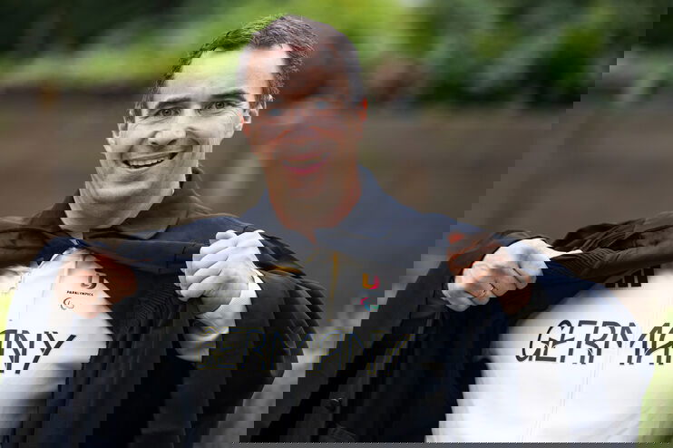 Eine als Mann lesbare Person präsentiert ein Germany-Trikot.