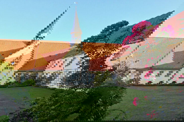 Ein Kloster an grünem Rasen unter blauem Himmel.