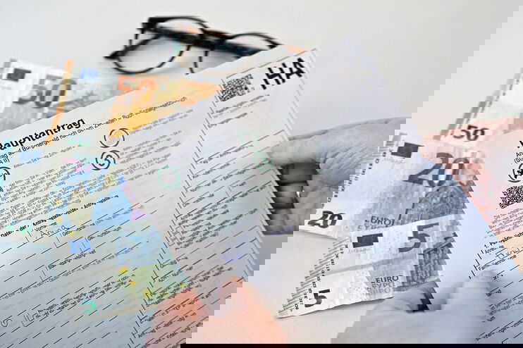 Ein Antrag auf Bürgergeld, im Hintergrund liegen Geldscheine
