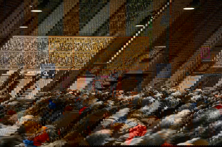 Eine Gruppe von Menschen diskutiert in einer vollen Kirche.