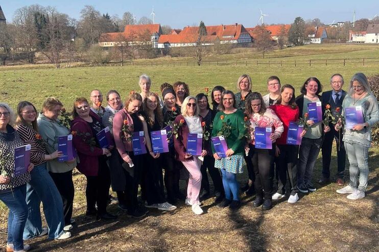 Etwa zwei Dutzend Menschen stehen auf einem Feld unter blauem Himmel.