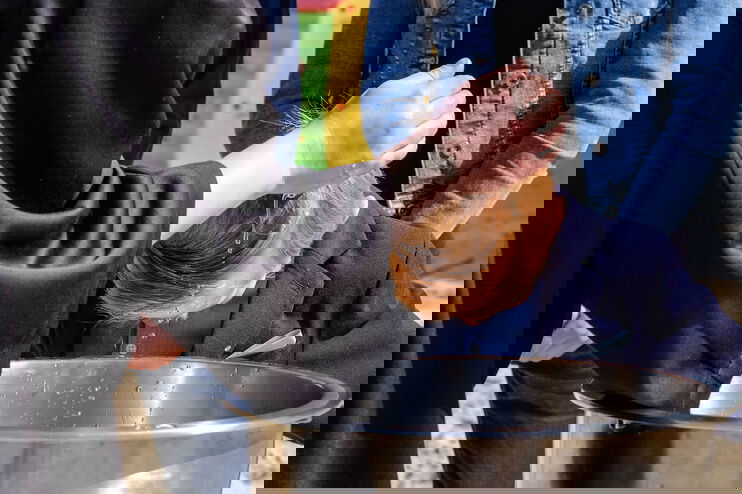 Eine Hand träufelt einem Täufling Wasser über den Kopf