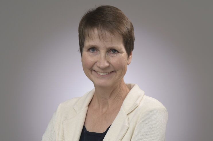 Eine als Frau lesbare Person im weißen Blazer.