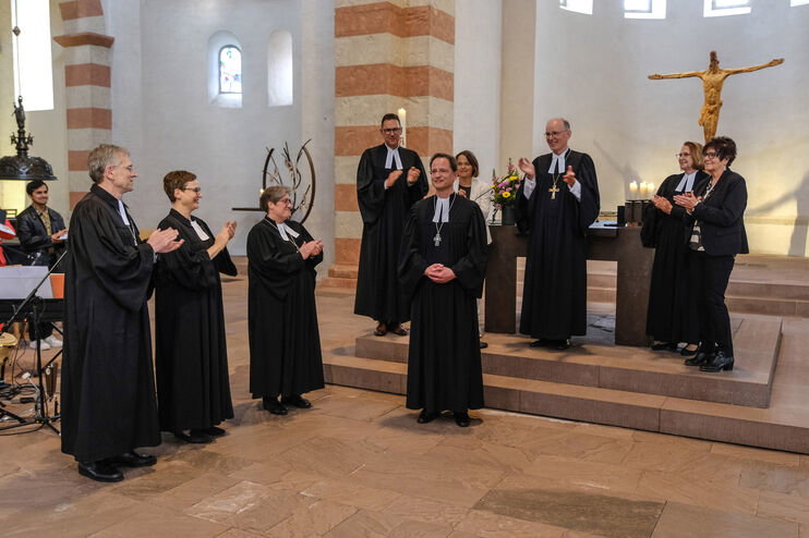 Mehrere als Männer und Frauen lesbare Personen stehen in einem Altarraum und applaudieren.