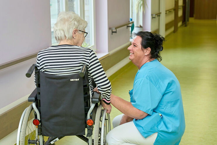 Pflegekraft mit einer Bewohnerin in einem Pflegeheim.
