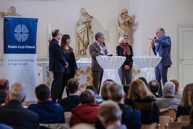 Eine Gruppe steht an Stehtischen und diskutiert.