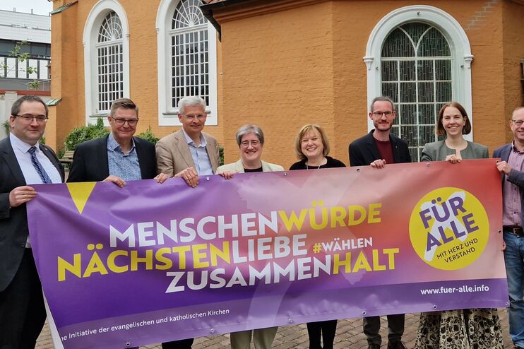 Mehrere als Frauen und Männer lesbare Personen halten ein Banner mit den Worten Menschenwürde, Nächstenliebe, Zusammenhalt