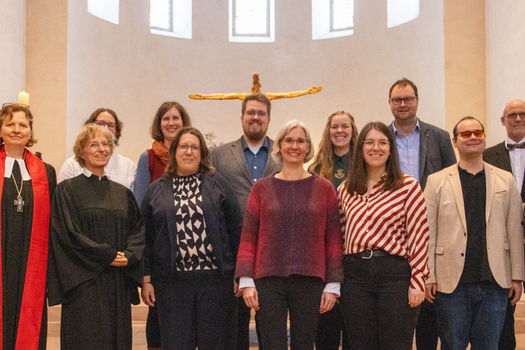 Etwa ein dutzend Menschen stehen zusammen in einer Kirche.