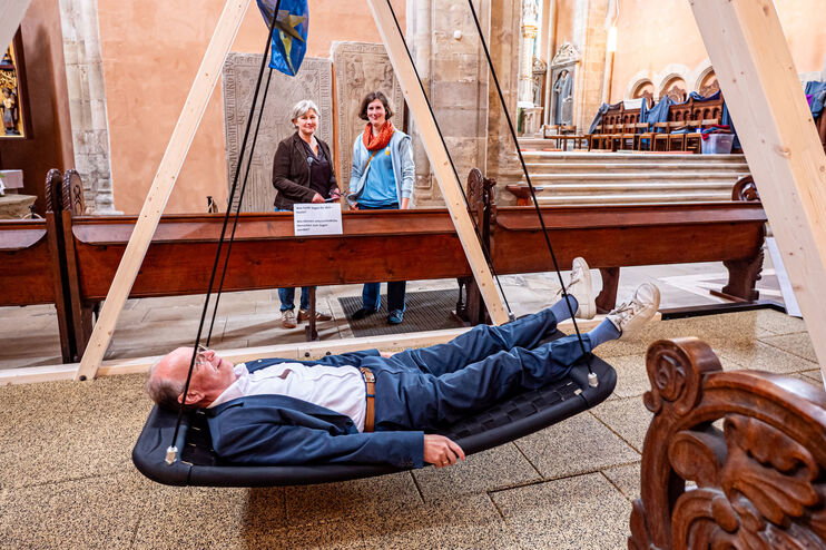 Eine als Mann lesbare Person in einer Schaukel in einer Kirche
