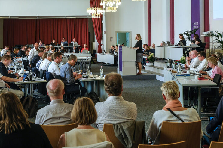Mehrere Menschen in einem großen Sitzungssaal