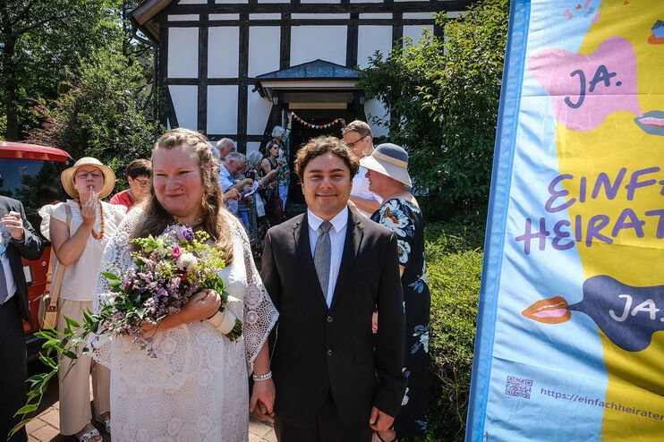 Eine Hochzeitsgesellschaft begrüßt ein Paar, das aus der Kirche kommt.