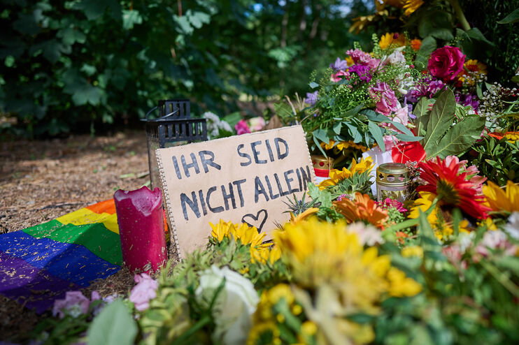 Blumen und Beileidsbekundungen, darunter ein Schild mit der Aufschrift: Ihr seid nicht allein.