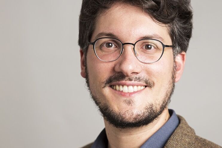 Eine jüngere als Mann lesbare Person mit Brille und braunen Haaren.
