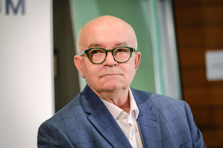 Eine als Mann lesbare Person mit Glatze und markanter Brille.