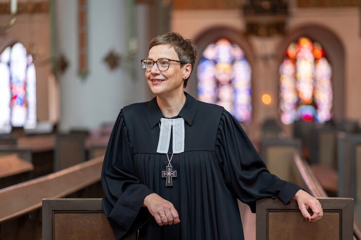 Eine als Frau lesbare Person im Talar in einer Kirche.