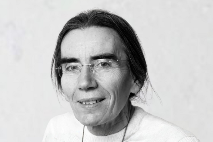 Eine weiblich gelesene Person mit langen zurückgebundenen Haaren und fassungsloser Brille.