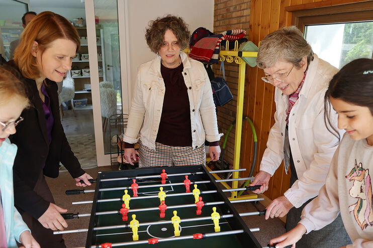 Drei erwachsene als Frauen und zwei als Mädchen lesbare Personen spielen Kicker 