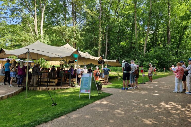Ein großes Zeltdach im Grünen, besucht von mehreren Menschen