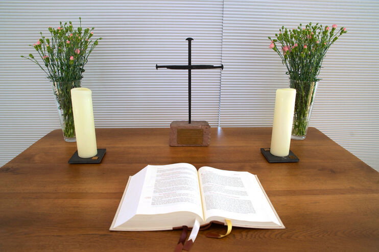 Ein Nagelkreuz auf einem Alter hinter einer aufgeschlagenen Bibel