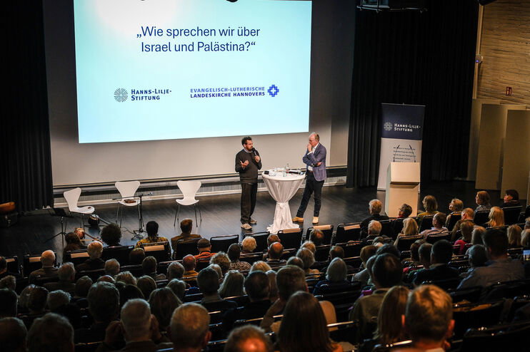 Zwei Menschen diskutieren auf einer Bühne vor Publikum