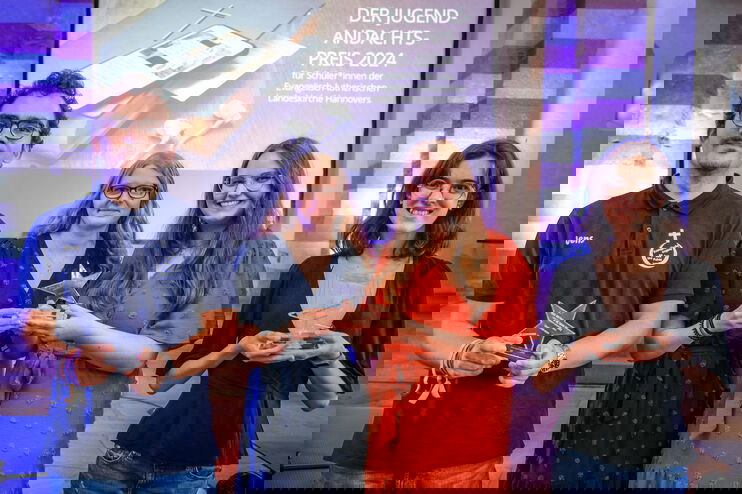 Vier junge Menschen posieren bei einer Preisverleihung mit einem Pokal.