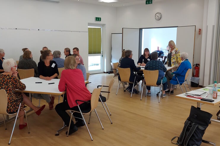 Menschen sitzen an Tischen in einem Raum.