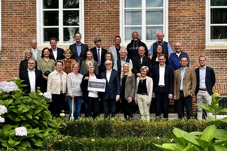Ein Gruppenbild mit mehr als 20 Personen vor einem Haus mit roter Klinkerwand.