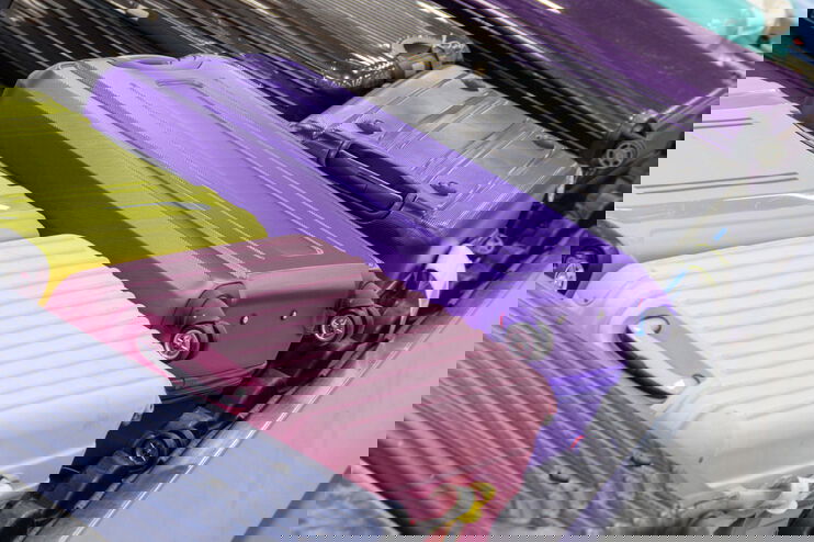 Man sieht bunte Koffer auf einem Gepäckband am Flughafen.