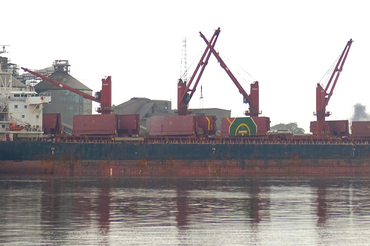 Ein Hafen mit Kränen und Gebäuden an grauem Wasser und grauem Himmel.