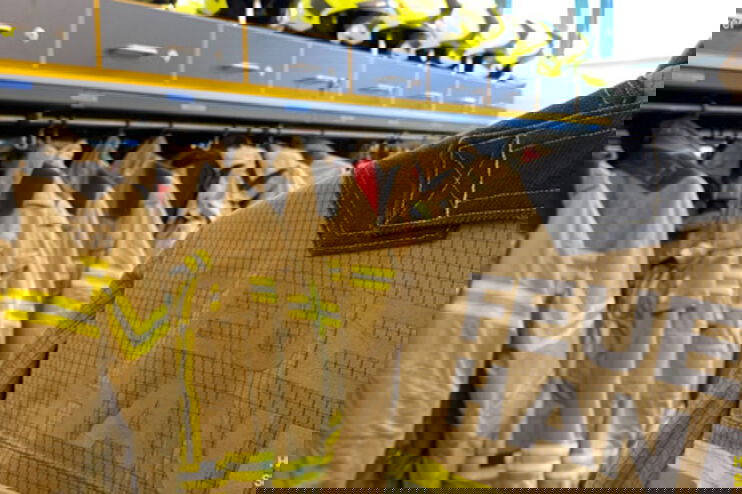 Gelbe Feuerwehrjacken hängen in einer Reihe in einem Schrank.