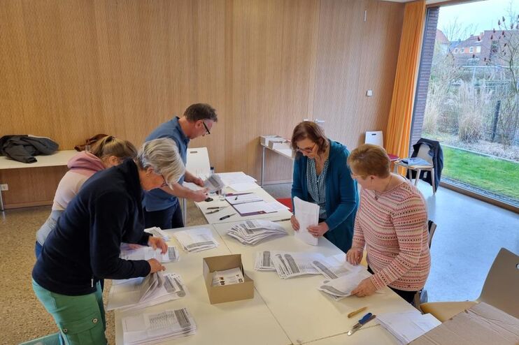 Fünf weiblich gelesene Personen beugen sich über einen Tisch, auf dem Zettel in verschiedenen Stapeln liegen.