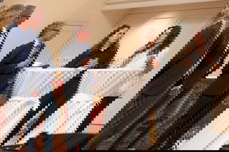 Mehrere junge und ältere Personen stehen an Stehtischen und diskutieren