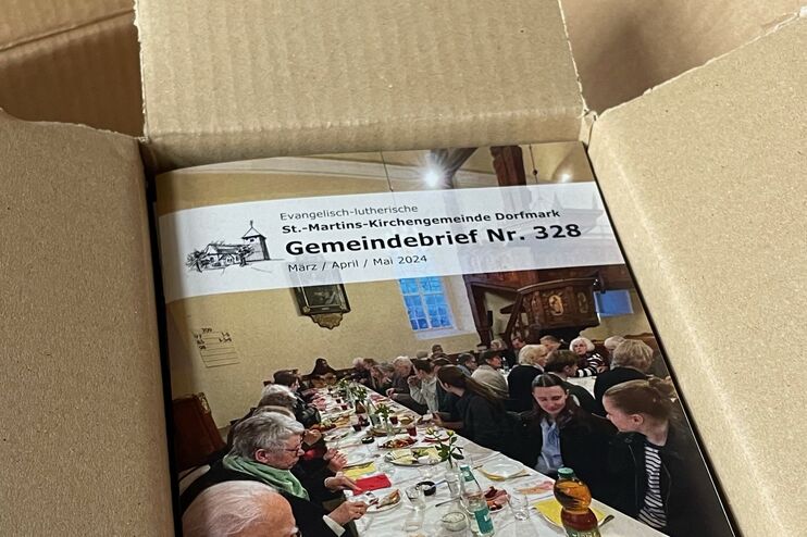 In einem geöffneten Karton liegen Broschüren.