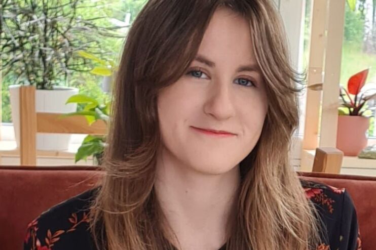 Ein junges Mädchen mit langen Haaren sitzt auf einer roten Couch