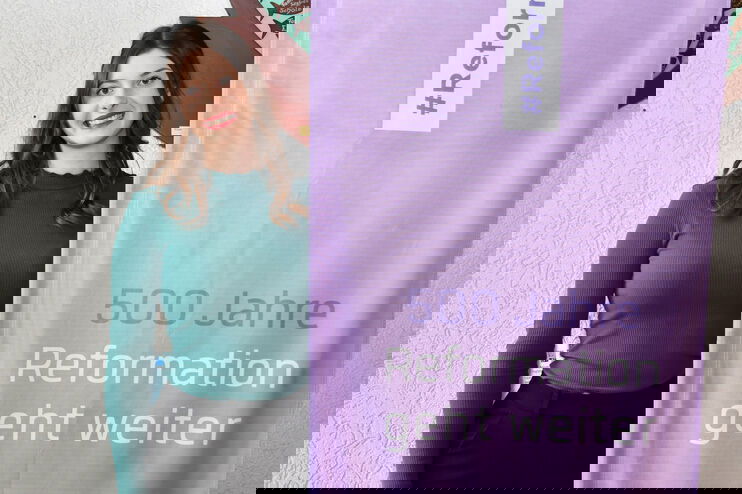 Eine als junge Frau lesbare Person steht neben einem lila Banner mit der Aufschrift "500 Jahre - Reformation geht weiter"