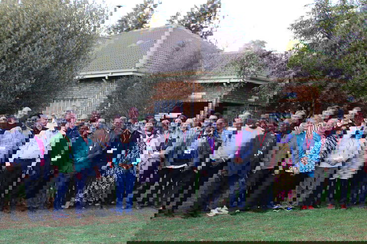Ein Gruppenfoto im Freien mit mehreren Menschen unterschiedlicher Hautfarbe.