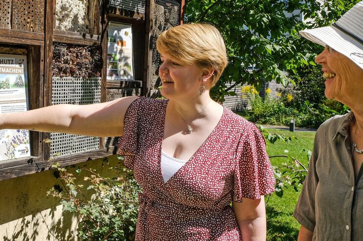 Zwei Menschen stehen im Grünen vor einem Insektenhotel. 