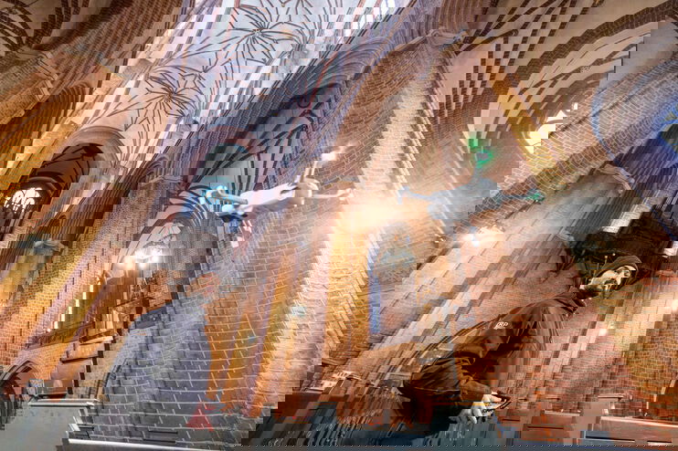 Eine als Mann lesbare Person lässt eine Drohne in einer Kirche fliegen.