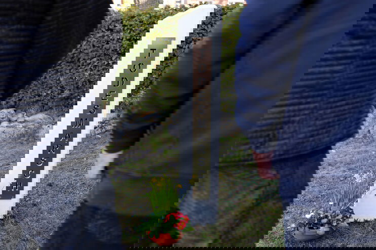 Zwei Menschen stehen vor einer Stele, auf der Todesmarsch steht.