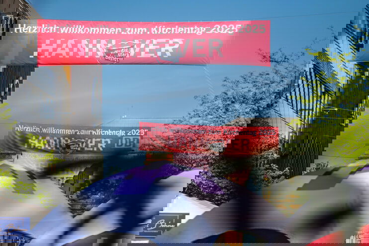 Ein Banner mit dem Kirchentagsschriftzug hängt über einer Straße.