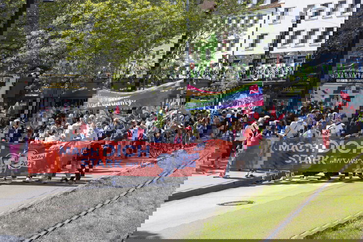 Ein Demonstrationszug mit vielen Menschen und Plakaten auf der Straße. 