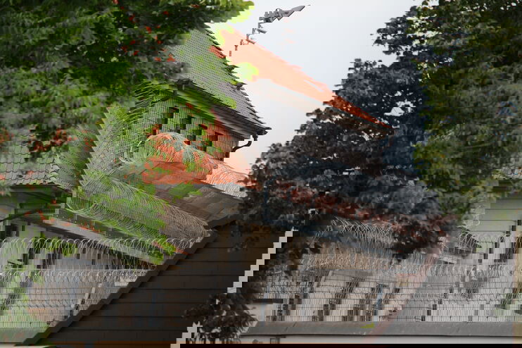 Ein Gebäude mit Stacheldraht drumherum zwischen Bäumen.