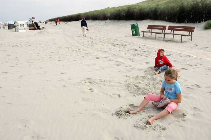 Zwei Kinder spielen im Sand am Meer.