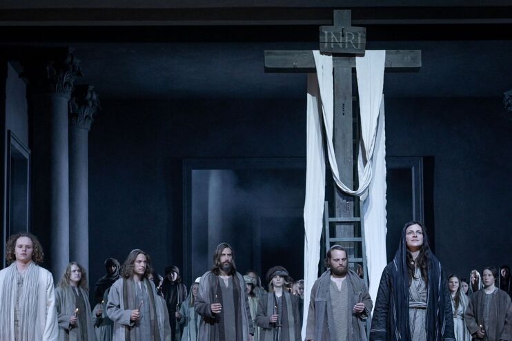 Menschen in Kostümen vor einem Kreuz.